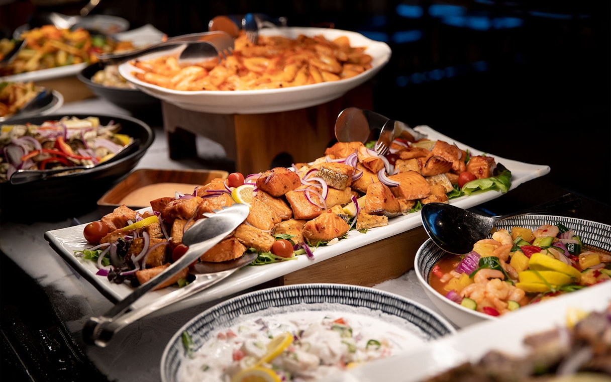 Te Puia buffet with salmon, vegetables, and traditional dishes in Rotorua, New Zealand.
