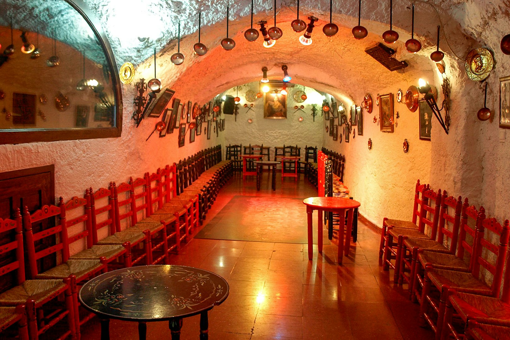 Flamenco Cuevas Los Tarantos performance area with red chairs and rustic decor.