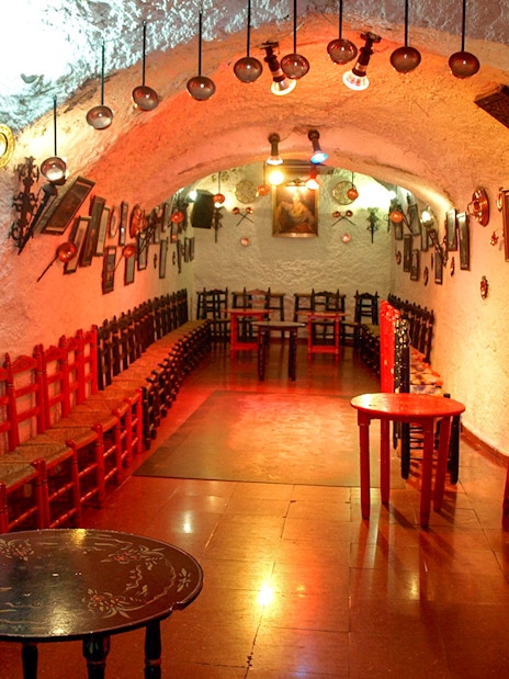 Flamenco Cuevas Los Tarantos performance area with red chairs and rustic decor.