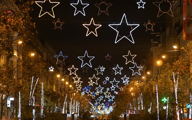 Star-shaped Christmas lights illuminate a city street during a festive tour.