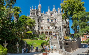 Visitors exploring gardens and architecture of Quinta da Regaleira, Sintra, Portugal.