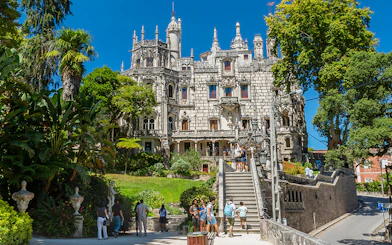 Visitors exploring gardens and architecture of Quinta da Regaleira, Sintra, Portugal.