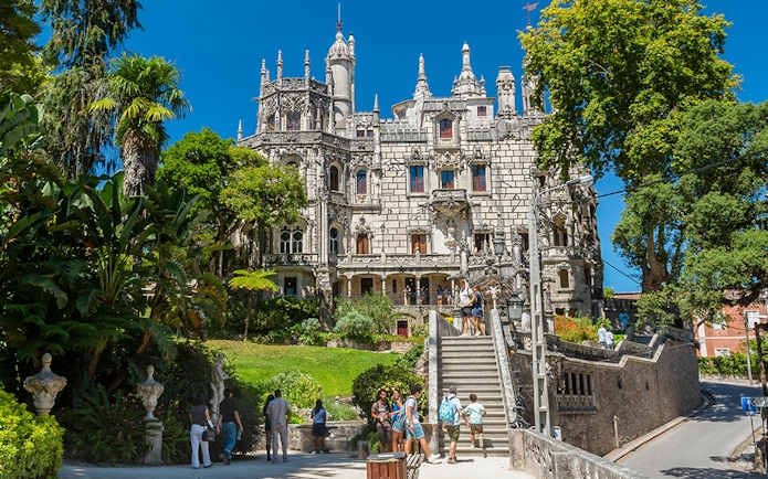 Visitors exploring gardens and architecture of Quinta da Regaleira, Sintra, Portugal.