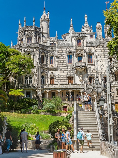 Visitors exploring gardens and architecture of Quinta da Regaleira, Sintra, Portugal.