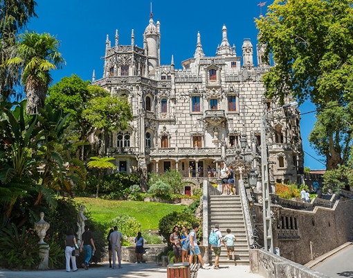 Visitors exploring gardens and architecture of Quinta da Regaleira, Sintra, Portugal.