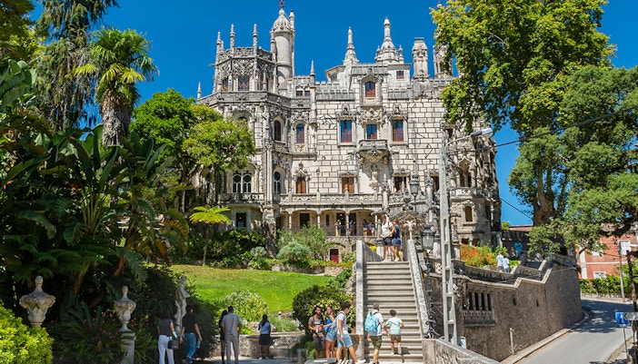 Visitors exploring gardens and architecture of Quinta da Regaleira, Sintra, Portugal.