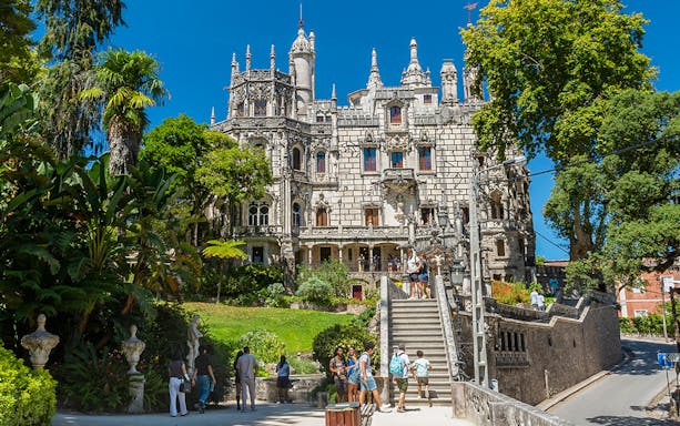Visitors exploring gardens and architecture of Quinta da Regaleira, Sintra, Portugal.