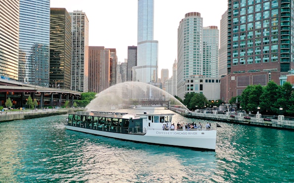 Odyssey Chicago River boat cruising on the Chicago River with city skyline.