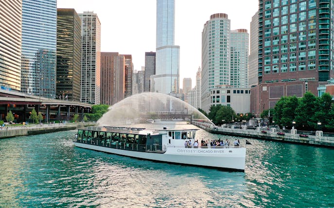 Odyssey Chicago River boat cruising on the Chicago River with city skyline.