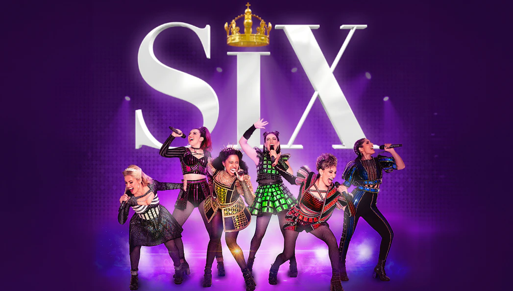 Performers in colorful costumes singing on stage with "Six" in the background.
