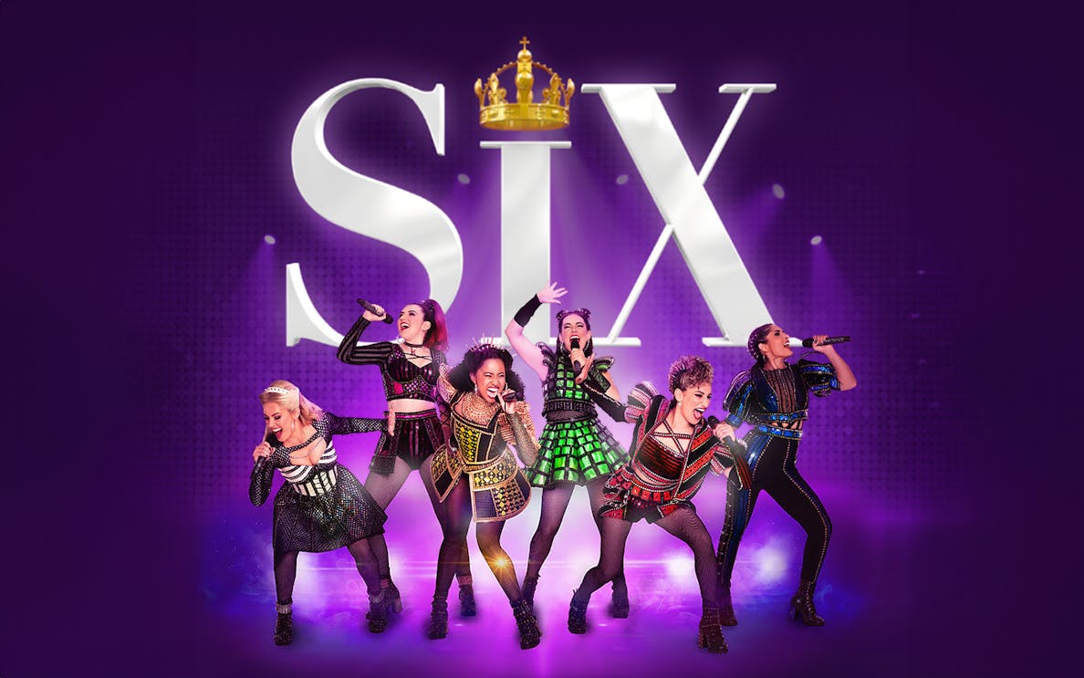 Performers in colorful costumes singing on stage with "Six" in the background.