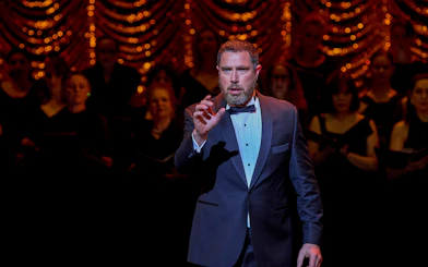 Performer in a tuxedo on stage during My Fair Lady musical.