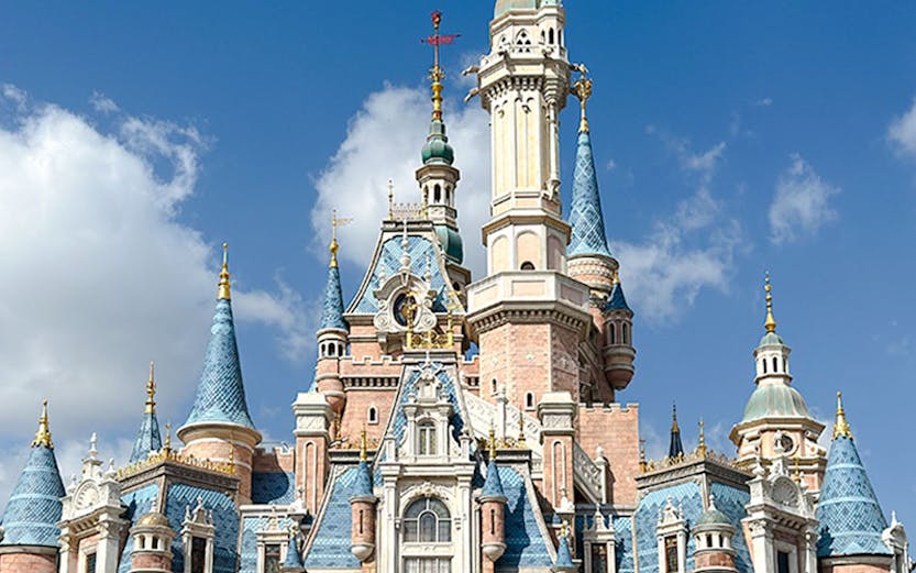 Enchanted Storybook Castle at Shanghai Disney Resort under a clear blue sky.