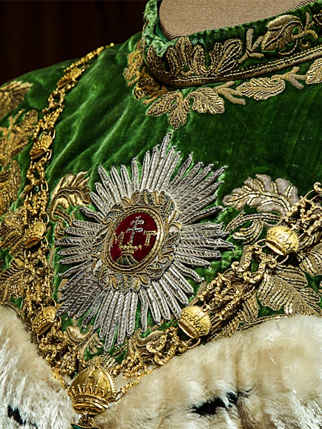 Ornate green and gold robe with intricate embroidery at Imperial Treasury Vienna.