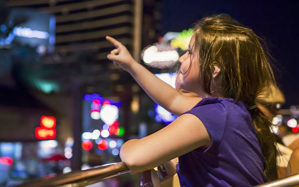Tourist pointing at city lights on San Francisco hop-on hop-off bus tour.