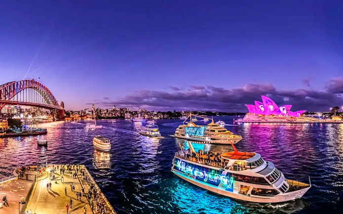 Cruise ships in Sydney Harbour with Opera House illuminated during Vivid Sydney festival.