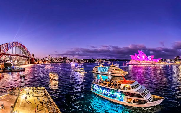 Cruise ships in Sydney Harbour with Opera House illuminated during Vivid Sydney festival.