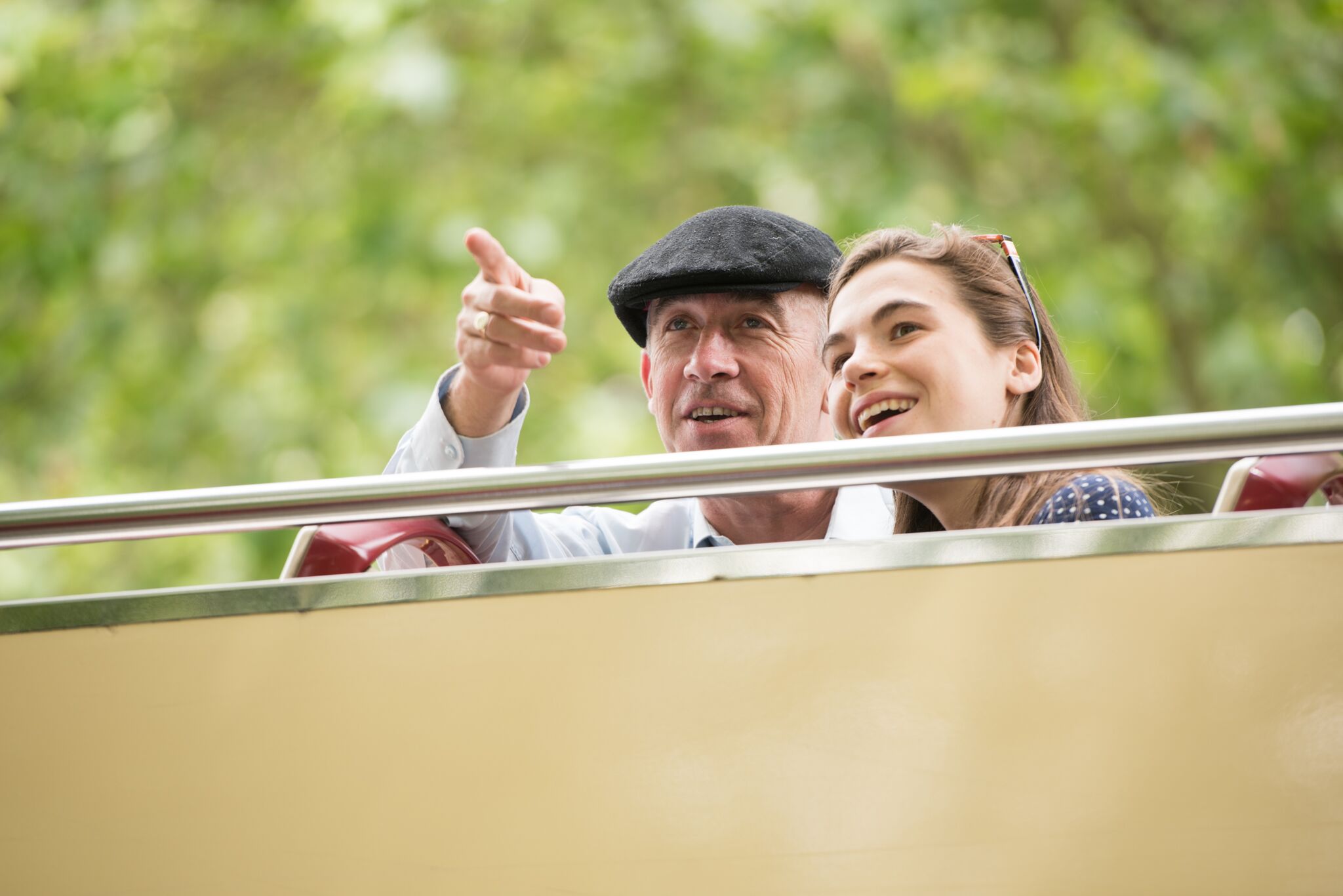 A couple holding a physical map navigating through the city standing near the hop on hop off bus