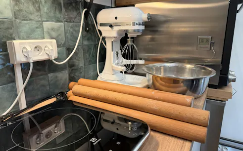 Kitchen setup for Paris croissant baking class with mixer, rolling pins, and bowl.