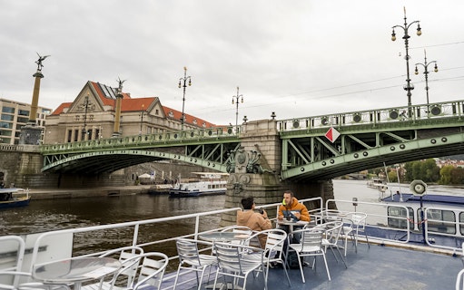 Guests enjoying views of a historic bridge during a boat tour in Prague.