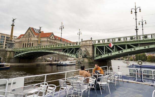 Guests enjoying views of a historic bridge during a boat tour in Prague.