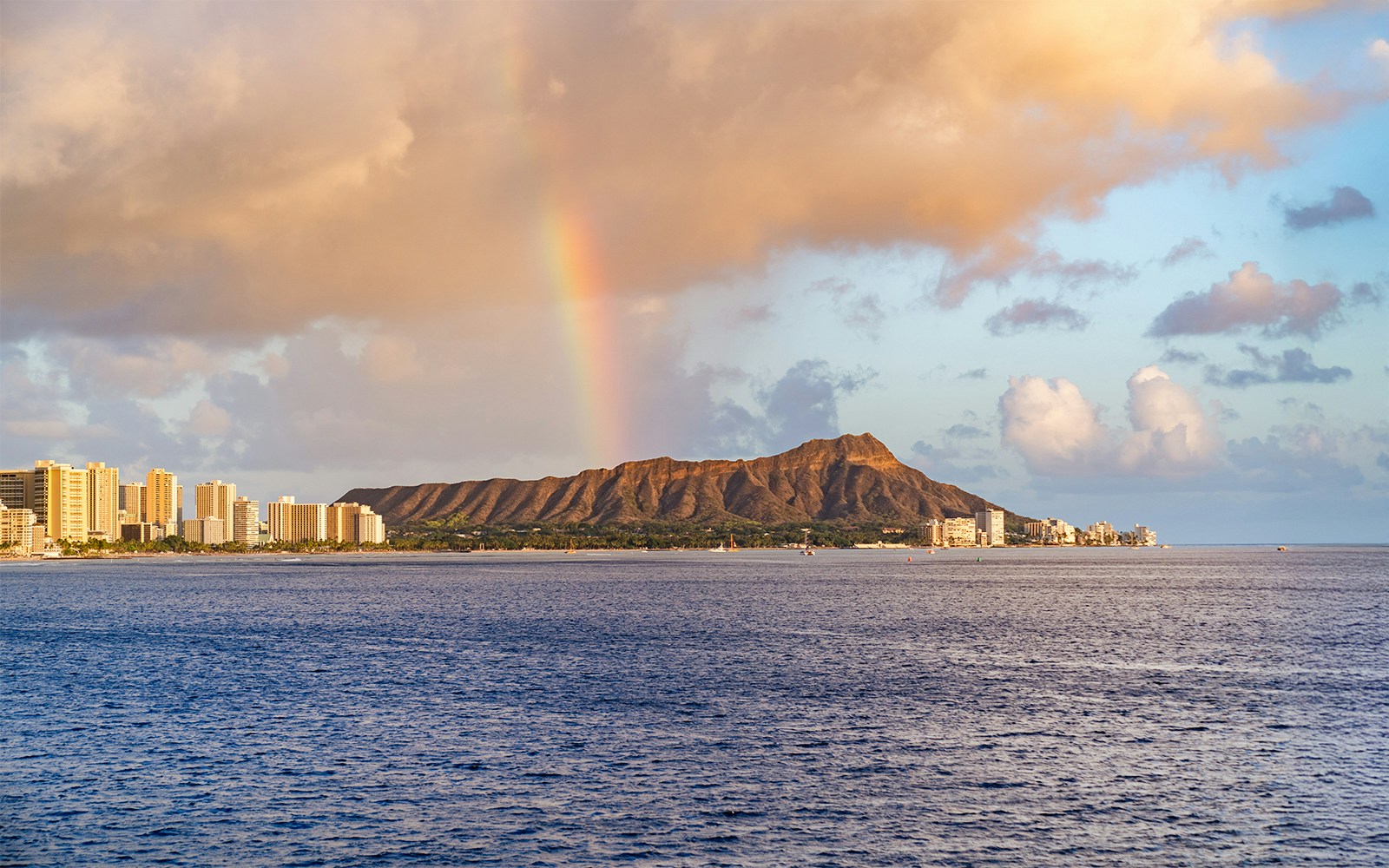 Rainbow over Diamond Head mountain at sunset, viewed from a cruise in Honolulu.