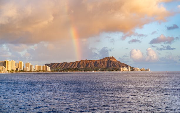 Rainbow over Diamond Head mountain at sunset, viewed from a cruise in Honolulu.