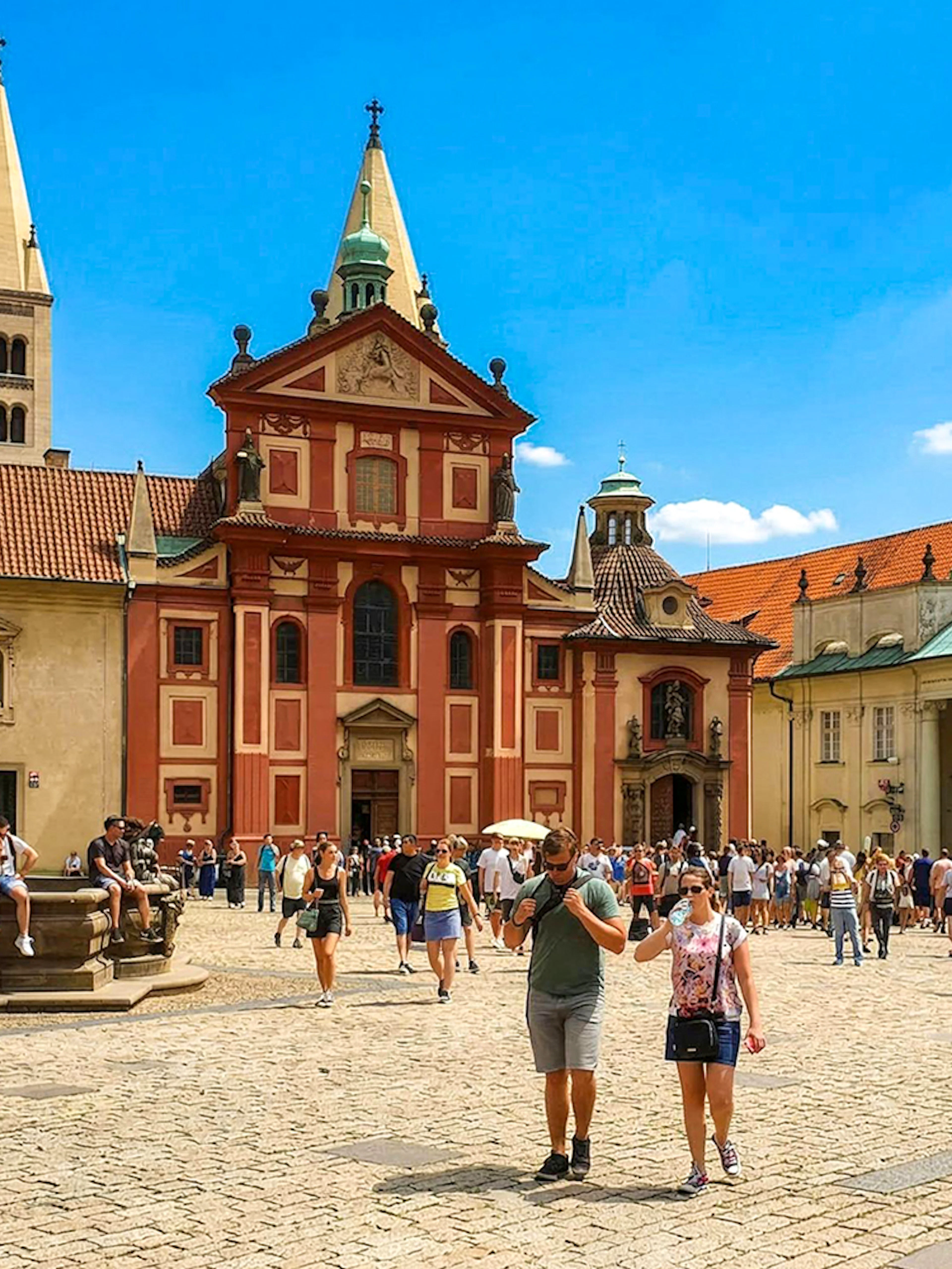 Guests walking in the courtyard of Prague Castle with historic buildings in view.