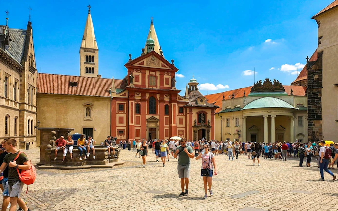 Guests walking in the courtyard of Prague Castle with historic buildings in view.