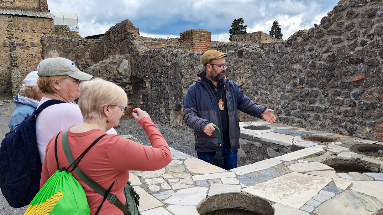 Tour guide explaining ancient ruins to visitors in Pompeii, Italy.