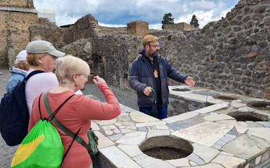Tour guide explaining ancient ruins to visitors in Pompeii, Italy.