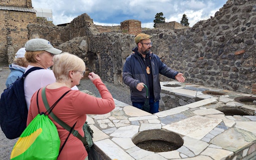 Tour guide explaining ancient ruins to visitors in Pompeii, Italy.