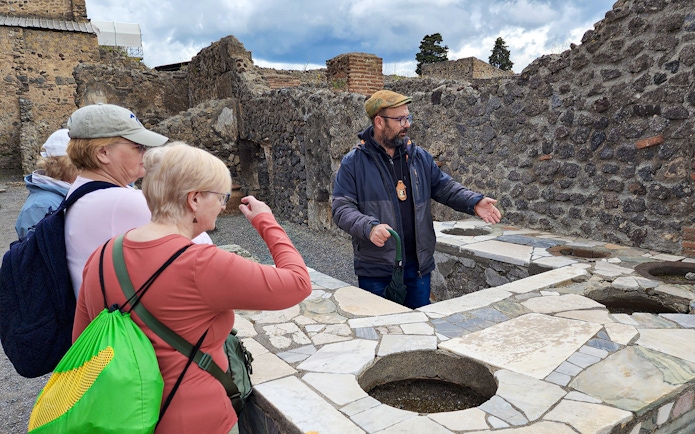 Tour guide explaining ancient ruins to visitors in Pompeii, Italy.
