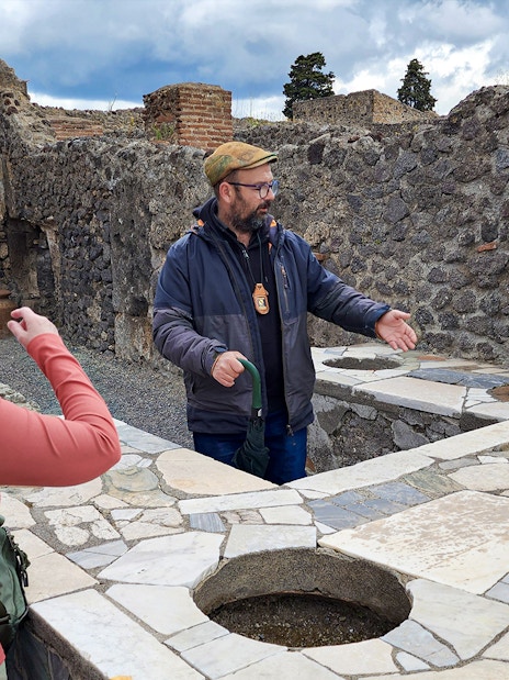 Tour guide explaining ancient ruins to visitors in Pompeii, Italy.
