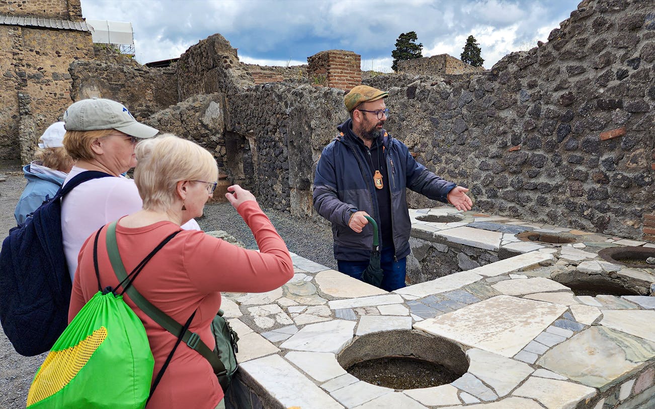 Tour guide explaining ancient ruins to visitors in Pompeii, Italy.