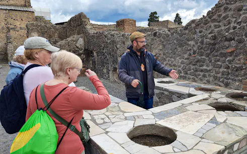 Tour guide explaining ancient ruins to visitors in Pompeii, Italy.
