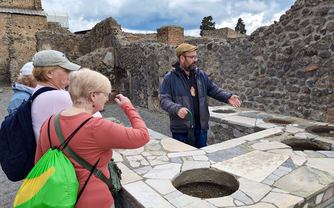 Tour guide explaining ancient ruins to visitors in Pompeii, Italy.
