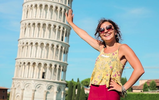 Smiling tourist posing with the Leaning Tower of Pisa during a guided tour from Florence.