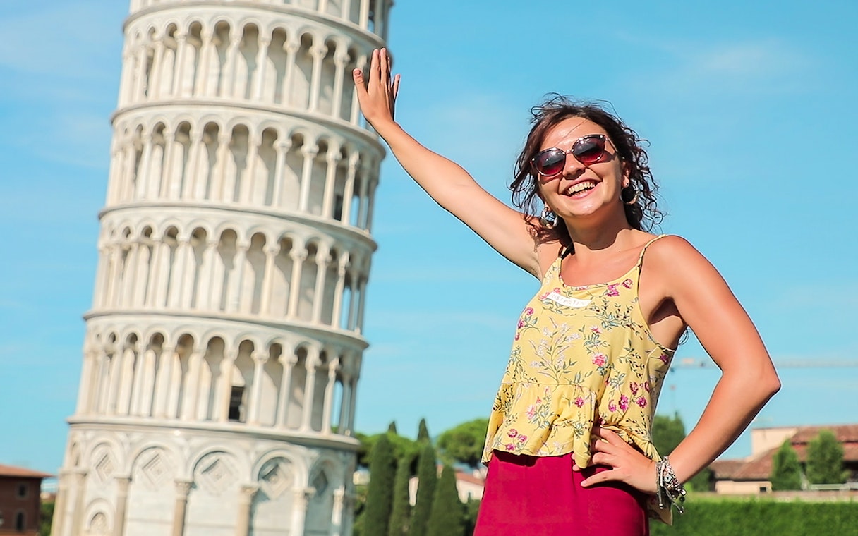 Smiling tourist posing with the Leaning Tower of Pisa during a guided tour from Florence.