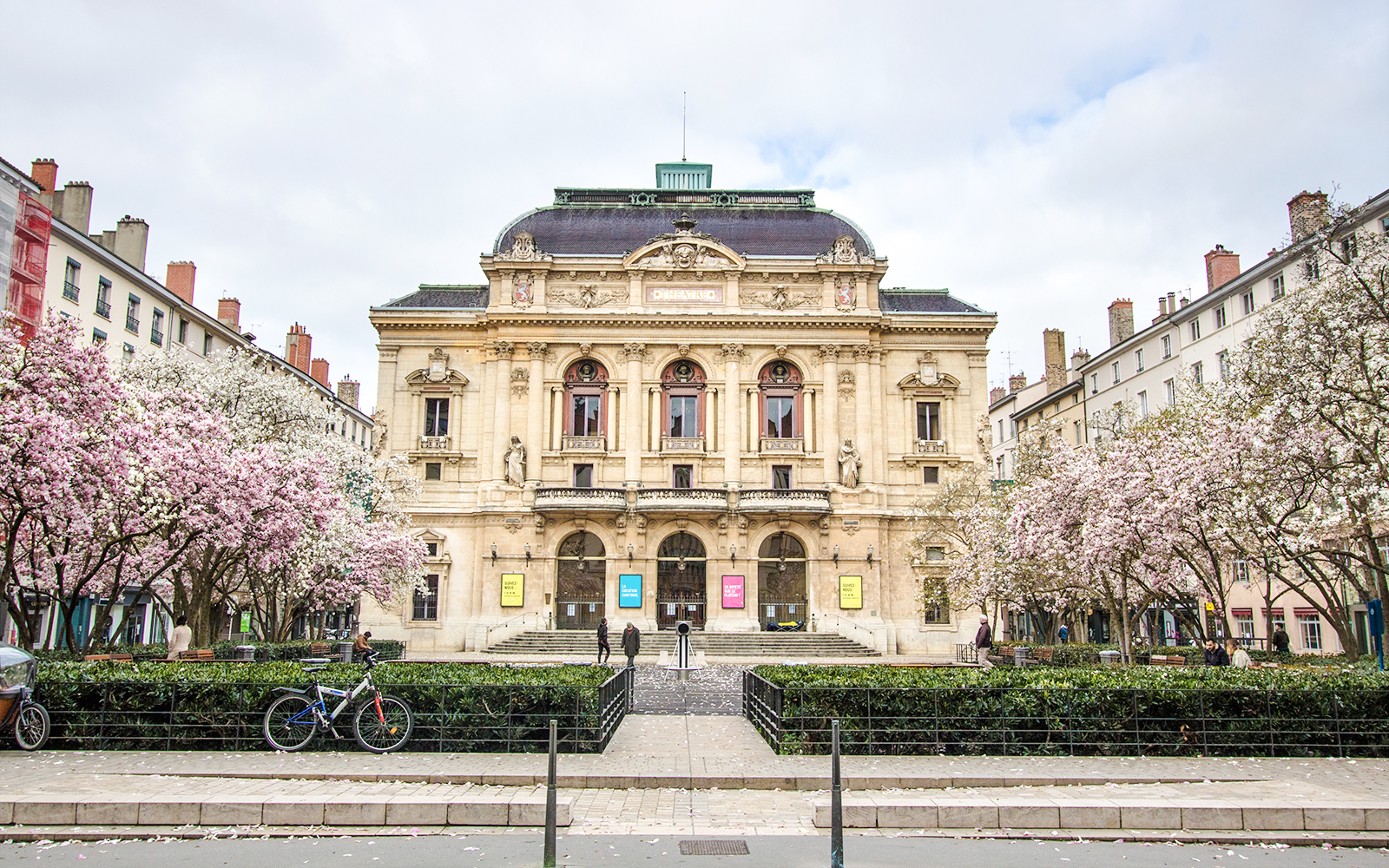 Théâtre des Célestins in Lyon with blooming trees and bicycles in front.