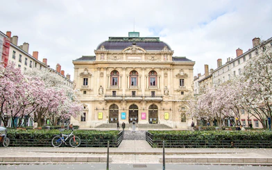 Théâtre des Célestins in Lyon with blooming trees and bicycles in front.
