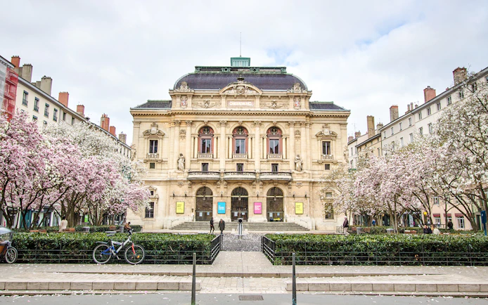 Théâtre des Célestins in Lyon with blooming trees and bicycles in front.
