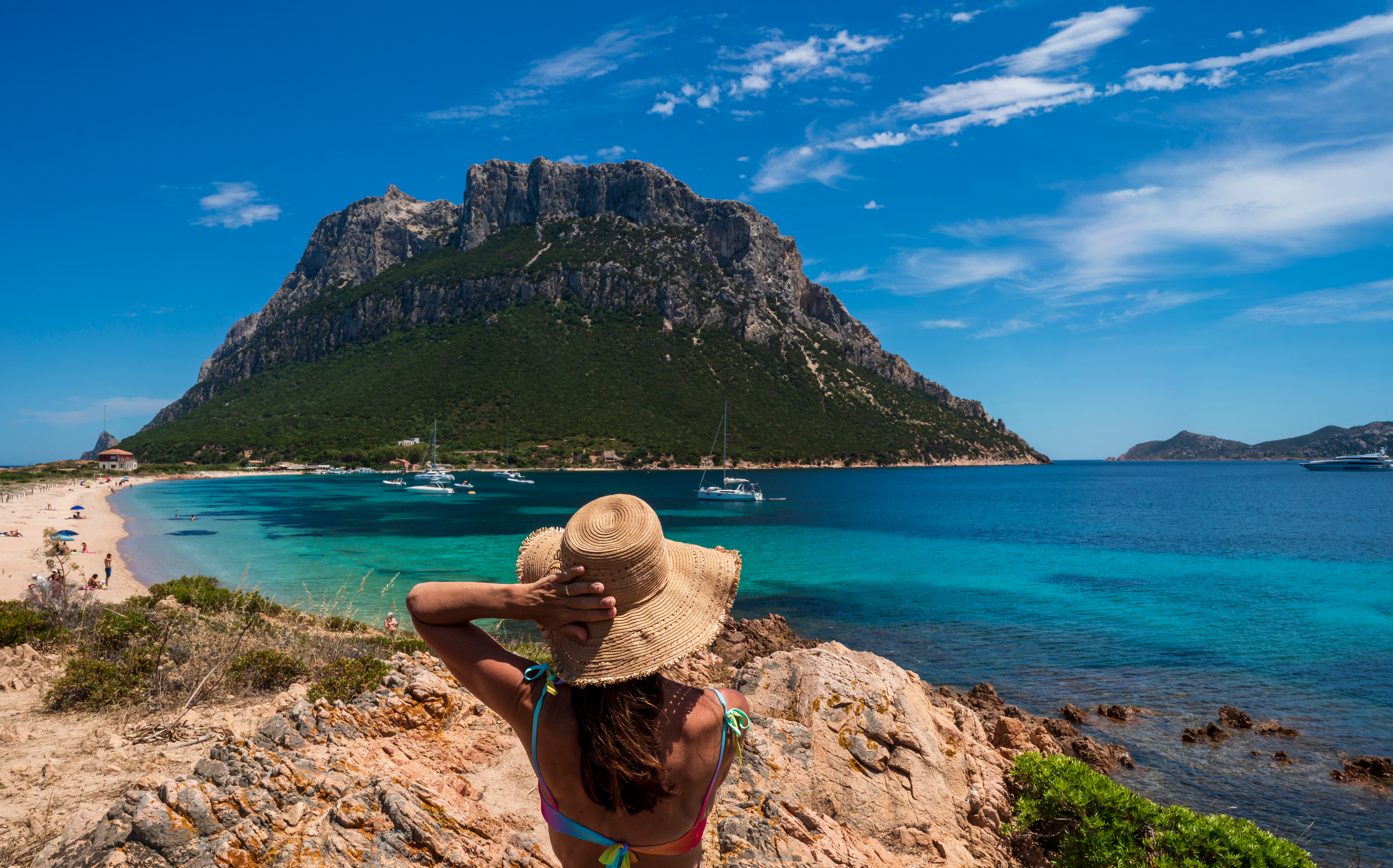 Girl in sun hat overlooking Tavolara Island beach and sea, Sardinia.
