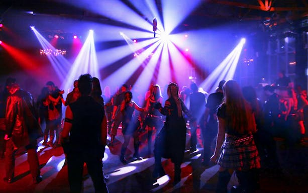 Nightclub crowd dancing under colorful lights.