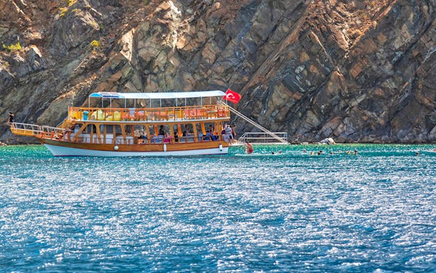 Guided boat tour near Lower Duden Waterfall, Antalya, with swimmers in the sea.