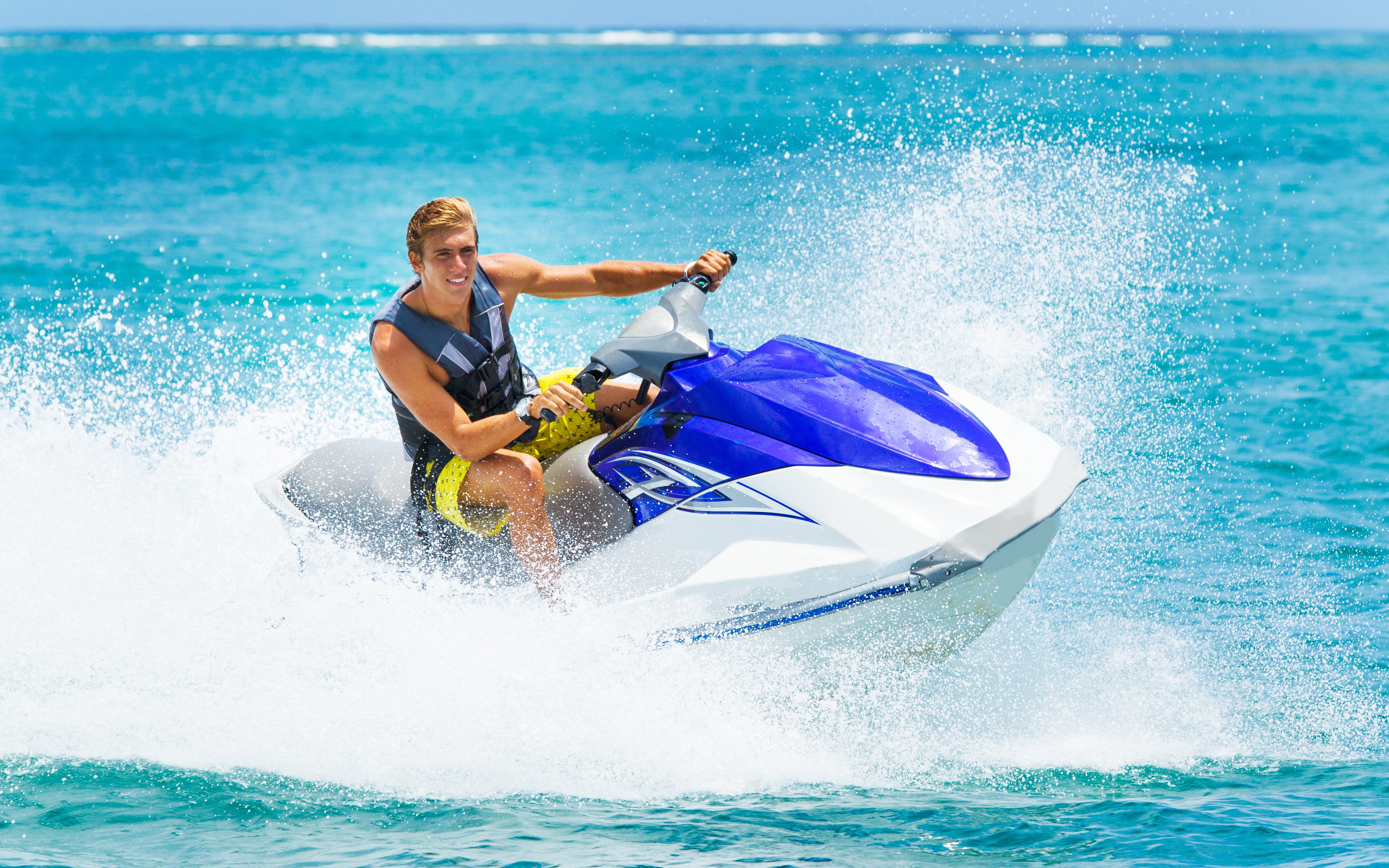 Young man riding a jet ski on clear blue ocean waters.