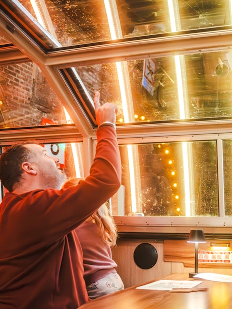 Man pointing at illuminated canal view during Amsterdam Light Festival cruise.