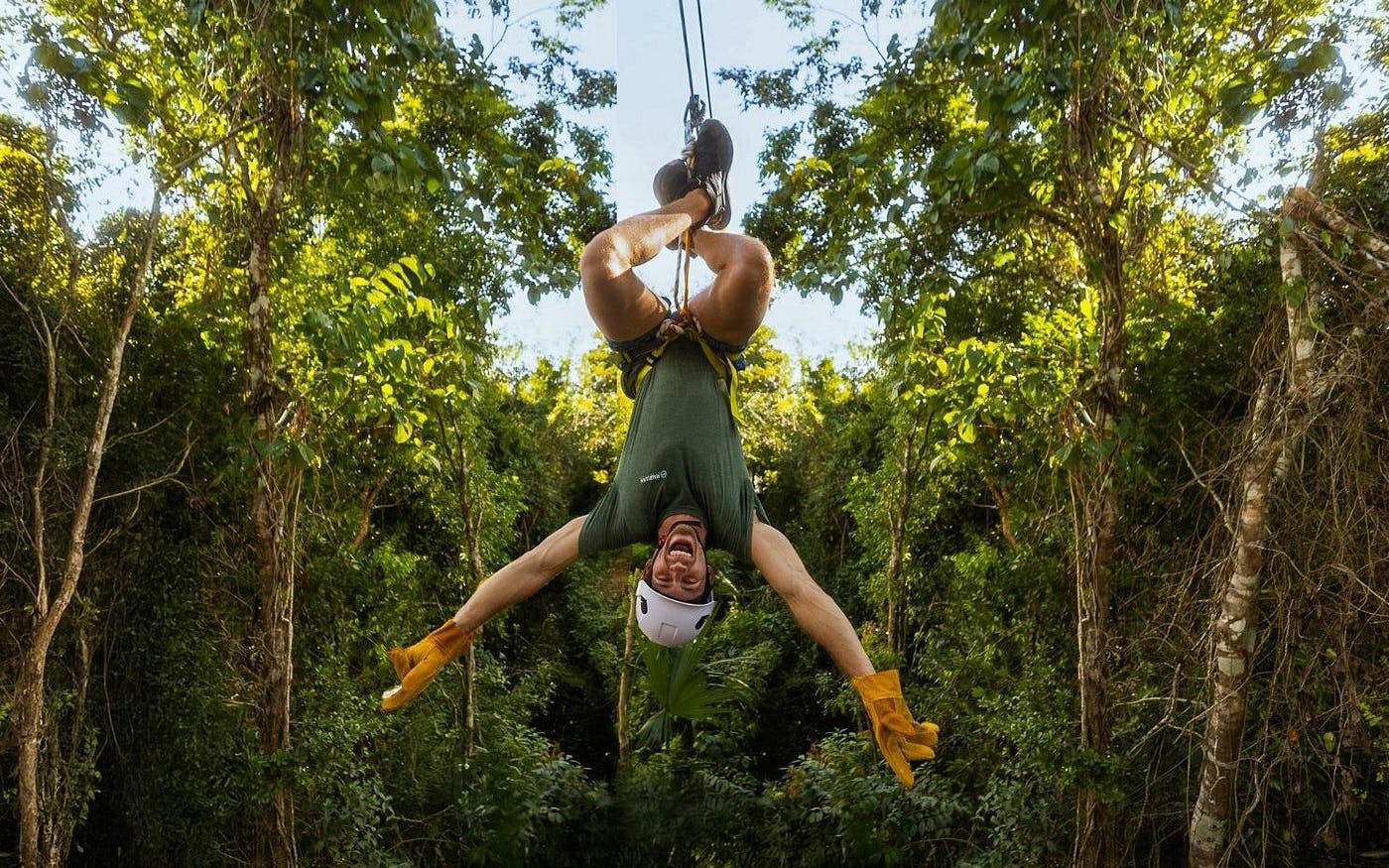 Ziplining upside down through lush jungle in Cancun adventure.