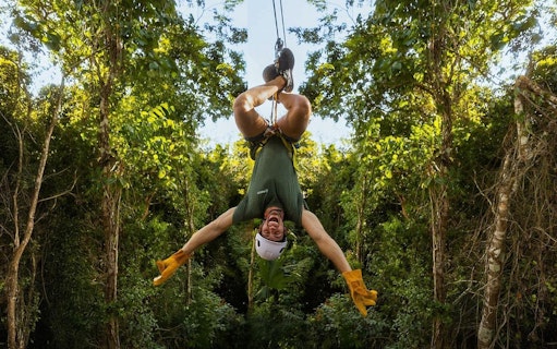 Ziplining upside down through lush jungle in Cancun adventure.