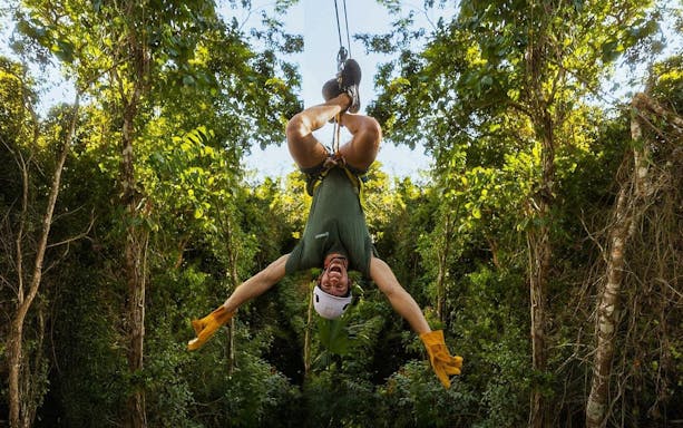 Ziplining upside down through lush jungle in Cancun adventure.